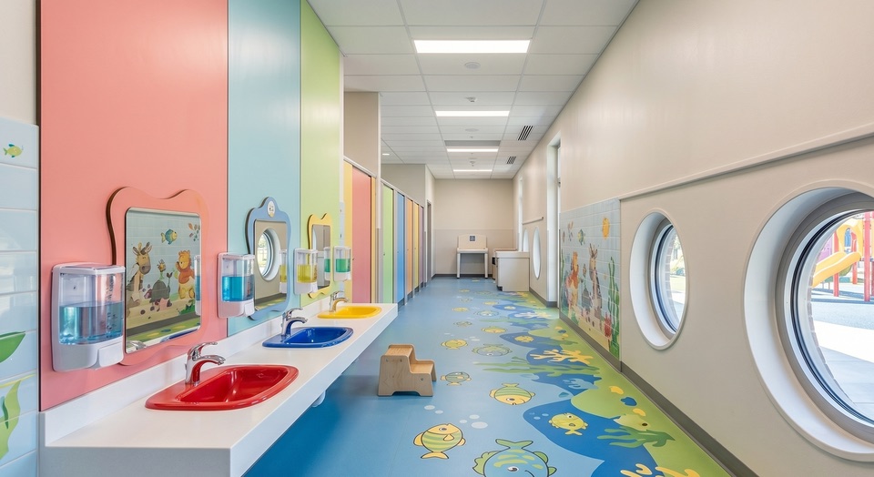 Kindgerechter Sanit&auml;rbereich: saubere Waschbecken in niedriger H&ouml;he, desinfizierte Griffe und gef&uuml;llte Spender